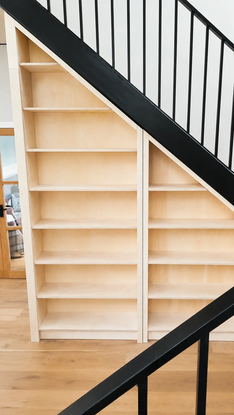 Birch plywood shelving fitted beneath a staircase with a black steel balustrade